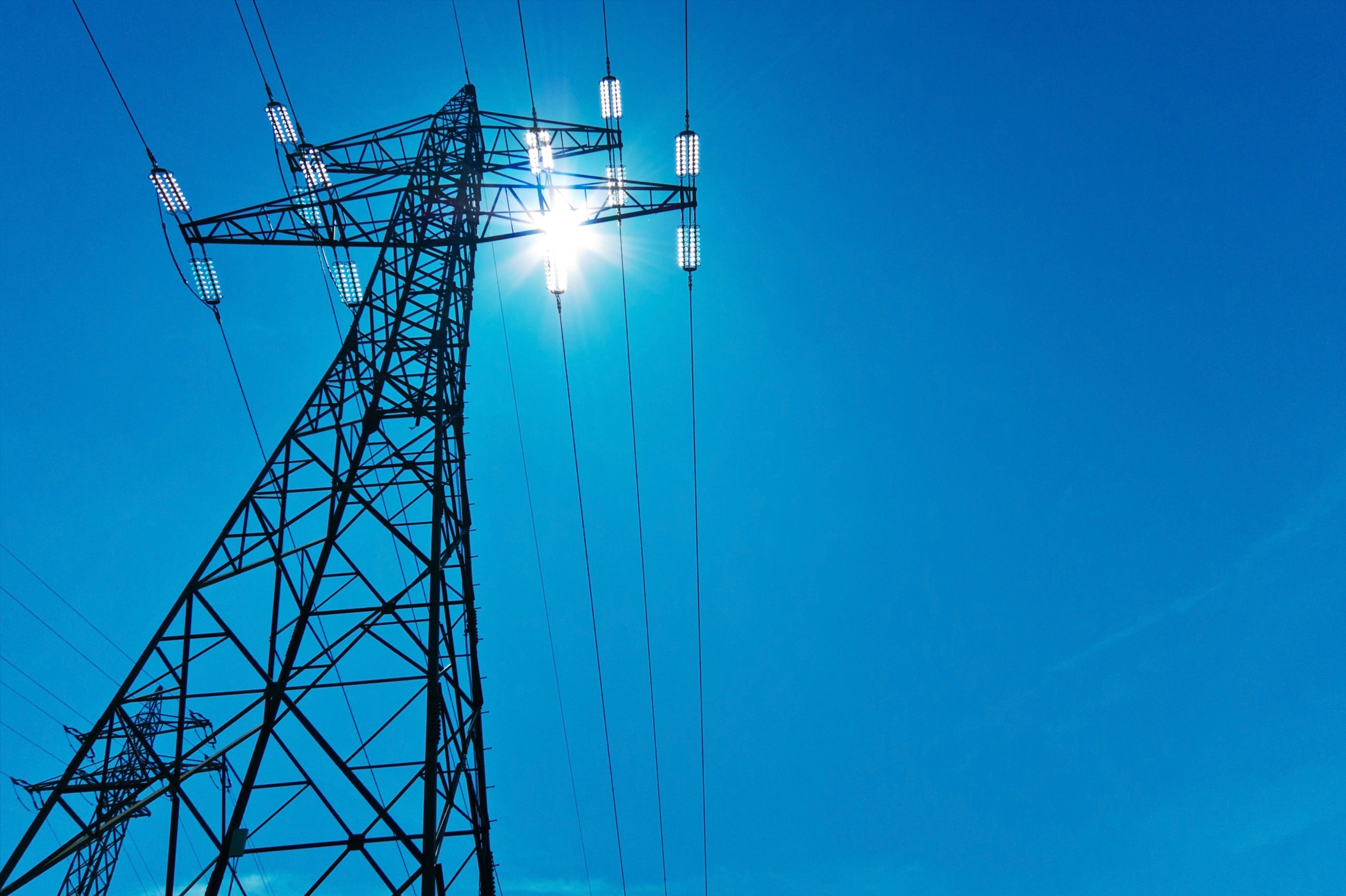 The,Power,Pole,High-voltage,Lines,With,Sun,And,Blue,Sky. utility electrical transmission tower